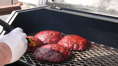 SmokingPit.com - The Colossal Trinity BBQ Surf & Turf burger - stuffed burger cooked over a oak wood fire on the Yoder YS640 Pellet cooker.- Mopping on the Motor City BBQ Trinity Sauce.