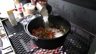 SmokingPit.com - Dutch oven Arroz Con Pollo cooked in a Lodge 12" dutch oven in my Scottsdale Santa Maria style cooker. Adding the long grain white rice.