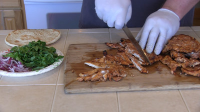 SmokingPit.com - Grilled Chicken Gyros with an authentic Greek Tzatziki sauce. Grilled over a Mesquite wood fire on the Scottsdale Santa Maria style cooker. Slicing the chicken.