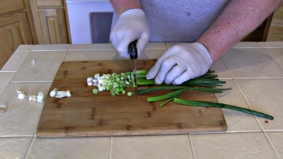 SmokingPit.com - Dungeness crab meat, bacon, garlic, green onion, gree pepper and postatoes fried with Creole seasoning. Slicing green onion.