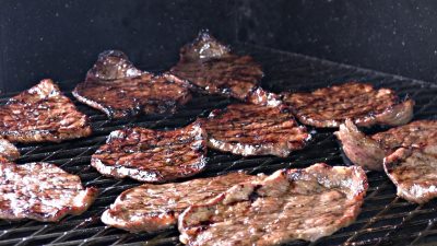 SmokingPit.com - Sesame Soy thin  sliced Beef Bottom Round Steak with a shrimp stirfry. Beef is cooked on a Santa Maria style  grill. Stir fry is done on a Wok in the grill. - Sesame Soy Beef grilling.